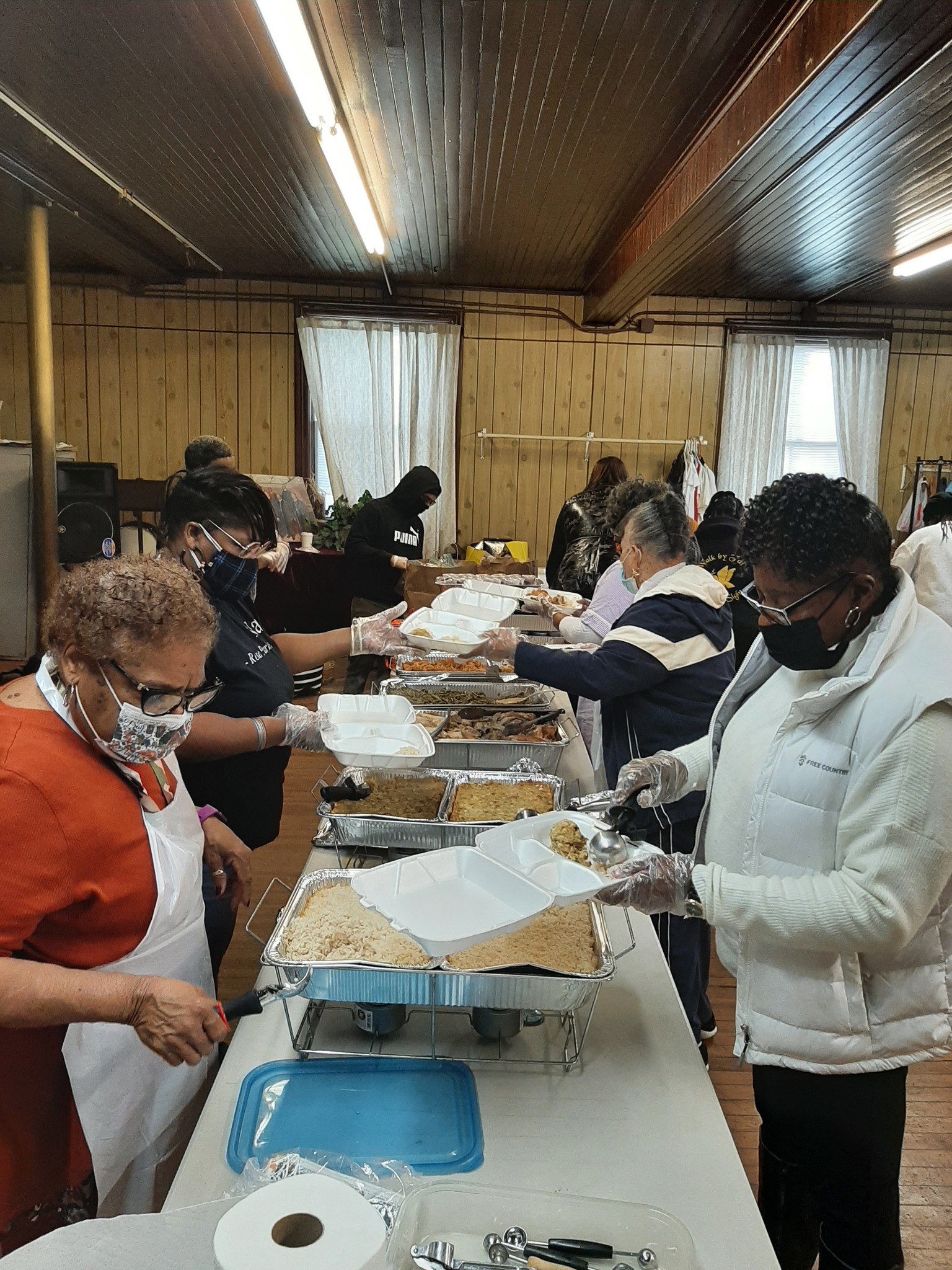 Volunteers serving hot meals along a buffet line at the community dinner